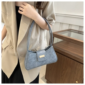 Detail view of grey minimalist underarm bag with gold buckle and suede texture