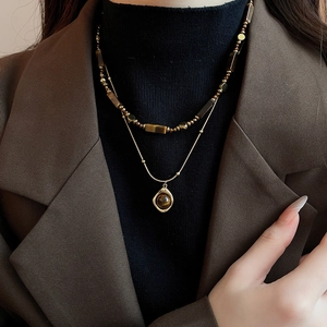 Double-layered gold necklace with tiger eye stone beads and irregular metal pendant