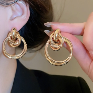 Macro shot of layered gold round hoop earrings with glossy metallic finish for women