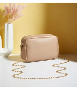 Close-up of beige crossbody bag with textured leather and gold chain strap detail