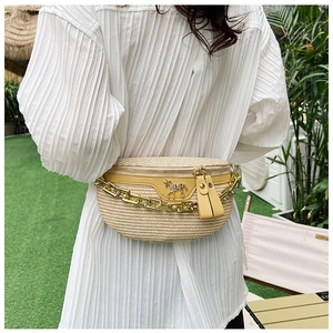 Detailed view of straw-woven crossbody bag with gold horse charm and chain on model