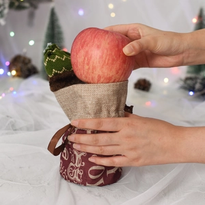 Christmas drawstring apple gift bag made of red and beige linen fabric shown in hands