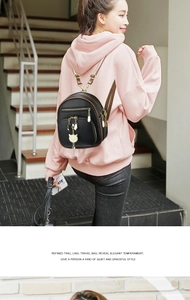 Mini black backpack with brown leather straps and cute cat metal charm on a pink hoodie