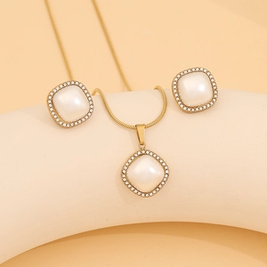 Detail of square faux pearl pendant and earrings set with crystal pavé on golden metal