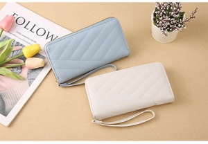 Flat lay of light blue and white V-quilted long wallets with wrist straps and gold zippers