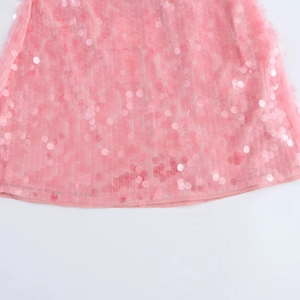 Dettaglio di paillettes rosa sull'orlo in mesh del mini abito con texture scintillante