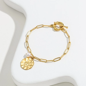 Golden OT buckle bracelet with white pearl and crowned heart pendant on stone stand