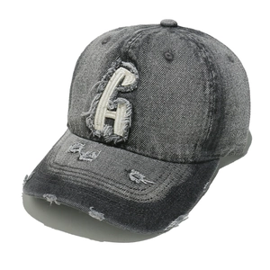 Close-up of vintage washed denim baseball cap with distressed details and large letter G