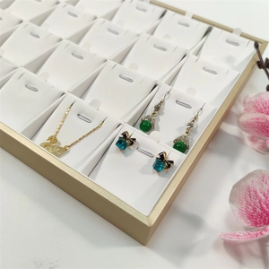 Detail of champagne gold jewelry tray with white leather slots for necklaces and earrings