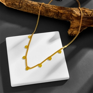 Detail of gold titanium heart necklace displayed on a white stand with rustic branches