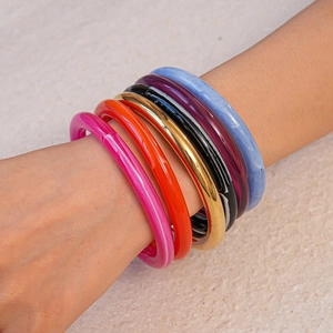 Vue rapprochée de bracelets en résine acrylique colorée et métal doré sur le poignet