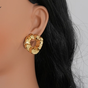 Detailed close-up of golden irregular lava texture hoop earrings worn on a model