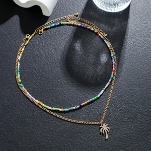 Close-up of layered necklace with colorful beads and a golden palm tree pendant