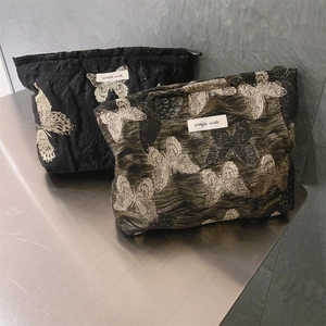 Nahaufnahme von Vintage-Kosmetiktaschen in Schwarz und Olivgrün mit feiner Schmetterlingsstickerei