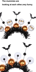 Detail of Halloween headband featuring mummy motifs, orange disco balls, and black bats
