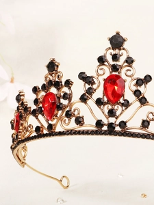 Close-up of vintage gold tiara with red teardrop gems and black decorative crystals
