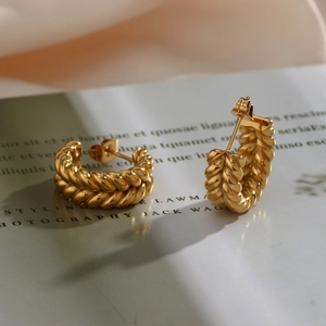 Macro detail of 18K gold plated C-shape hoop earrings with twisted wheat pattern texture