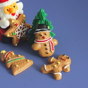 Macro shot of 5 resin Christmas figurines including gingerbread man and tree on blue background