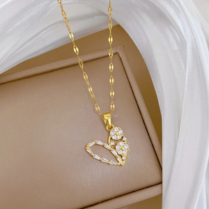 Close-up of gold heart pendant with sparkling crystals and elegant floral pattern