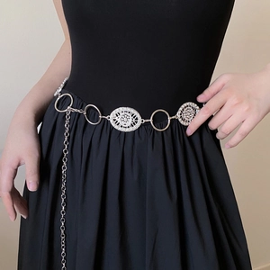 Vintage metal waist chain with ornate round motifs worn over a black dress
