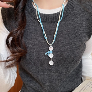Vue détaillée du pendentif bonhomme de neige avec écharpe bleue et cordon en velours