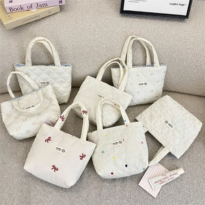 Flat lay of quilted mini tote bags with bow and heart embroidery on soft fabric