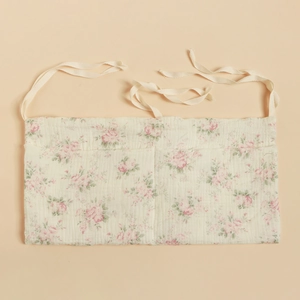 Detail of floral cotton hanging storage bag with two pockets and tie straps for crib