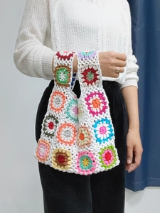 Detailed view of colorful granny square crochet stitches and cotton knit texture on a handbag
