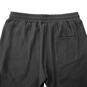Detail view of grey knit trousers featuring elastic waistband and vertical stripe texture