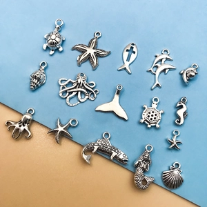 Vista macro de varios dijes marinos de plata con tortugas y estrellas de mar para joyería