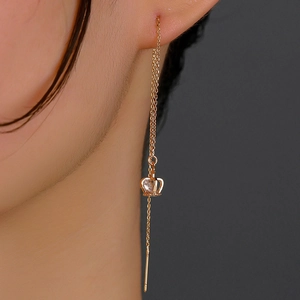 Detailed view of long gold tassel earrings with crown pendant and sparkling zircon