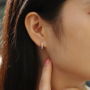 Close-up of a silver moissanite hoop earring featuring a double-row pavé setting on model