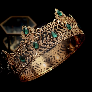 Detailed close-up of a golden hollow leaf crown set with emerald green oval gemstones