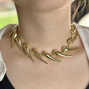 Edgy gold thorn necklace with spiked metal pendants shown on model neckline
