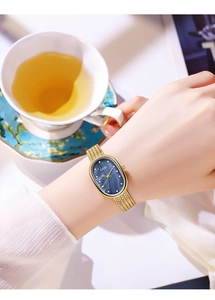Close-up of golden mesh strap watch with oval blue mother-of-pearl dial on woman's wrist
