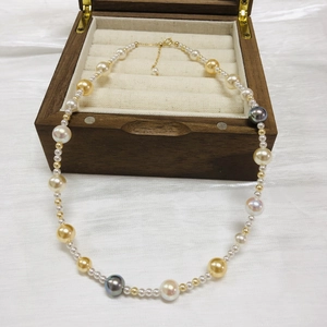 Detail of colorful mixed pearls in a luxury wooden box with adjustable gold chain