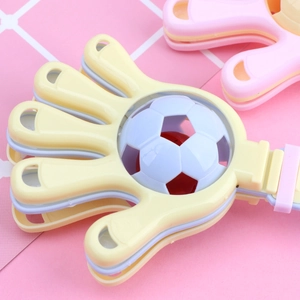 Close-up of yellow plastic hand clapper toy with decorative soccer ball detail