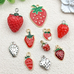Macro shot of 10 mini 3D strawberry charms in red resin and gold alloy for DIY jewelry