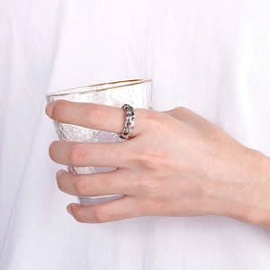 Close-up of a silver cuban link chain ring worn while holding a textured glass