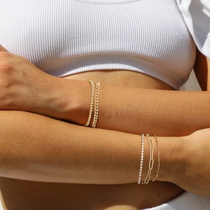 Detail shot of stacked gold titanium steel bracelets including paperclip and cuba link chains