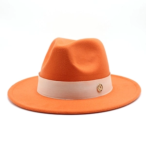 Close-up of orange wool fedora with beige decorative band and gold letter M logo