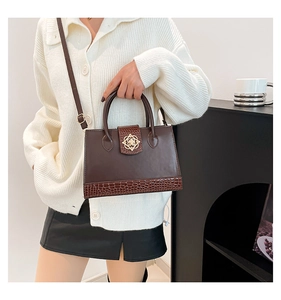 Detail of dark brown leather crossbody bag with vintage gold flower clasp and croc texture