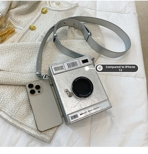 Détail du sac à bandoulière argenté en forme d'appareil photo sur une veste en tweed
