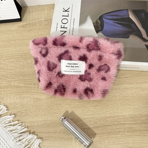 Pink heart leopard plush pouch displayed with accessories on a wooden desk setup
