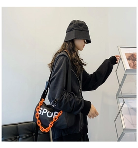 Sac bandoulière en nylon avec chaîne orange et logo SPORT porté dans un look urbain