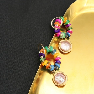 Bohemian colorful beaded hoop earrings with pearl charms on a golden display tray