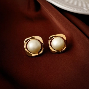 Close-up of vintage flower shaped golden earrings with white pearls on silk cloth