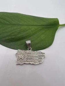 Detailed close-up of a Puerto Rico flag pendant with clear sparkling crystals on a green leaf