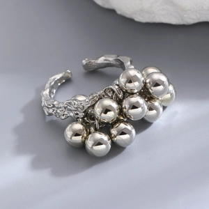 Macro detail of silver ring with irregular textured band and clustered spheres on stone