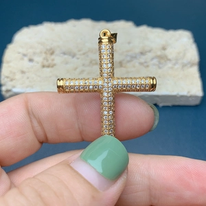 Detailed macro view of an 18k gold-plated cross pendant with pave-set zircon stones